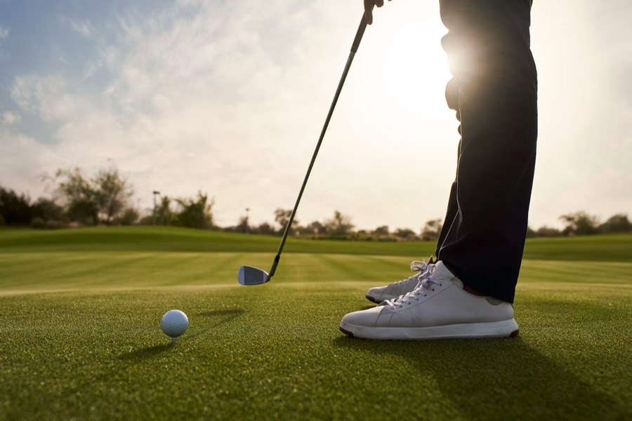 A golfer at address in warm backlight, about to play a shot.