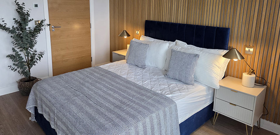 Navy velvet headboard bedroom with wood slat feature wall