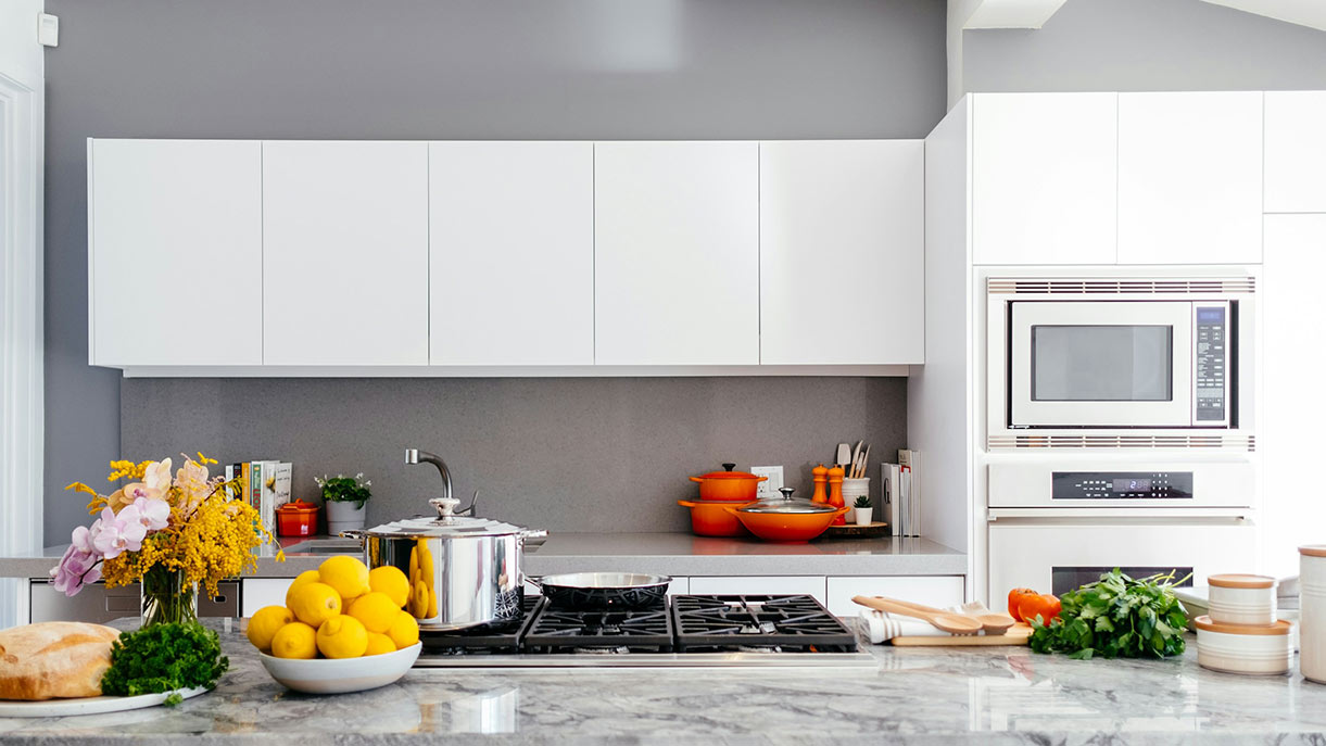 Kitchen with orange cookware, fresh produce and marble countertop