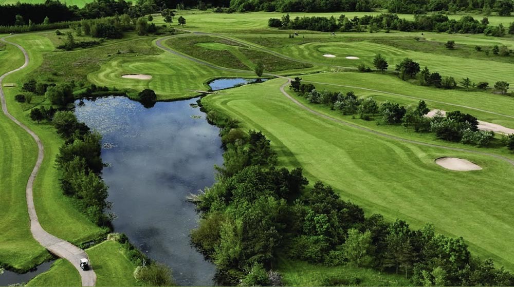 Aerial view of Longhirst Golf Club, Morpeth, with a water hazard winding through the fairway.