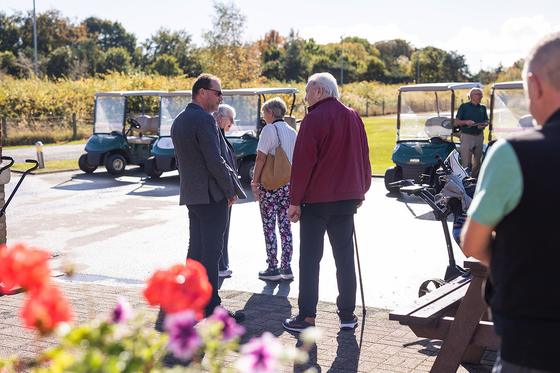 Guests arriving outside the clubhouse, with buggies lined up behind them