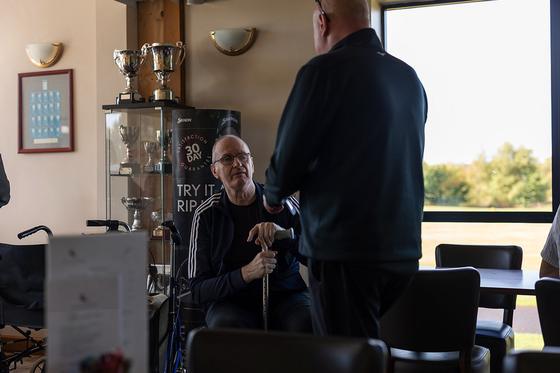 A guest in conversation beside the trophy cabinet